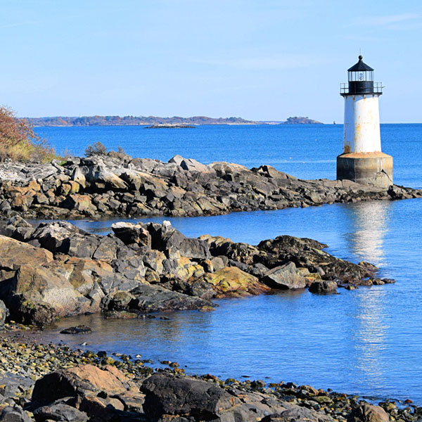A peaceful view of a lighthouse along the rocky shores of Marion, MA, symbolizing trusted, guiding dental care for local families - dentist marion ma